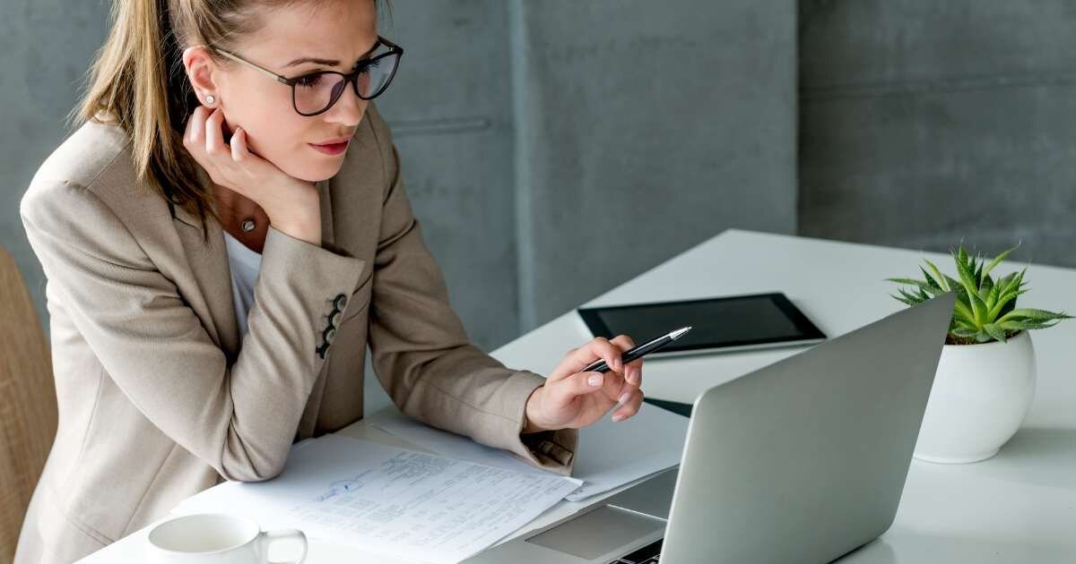 A women in office attire sitting at a desk on her laptop 